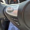 Close-up of the 2018 Nissan Sentra SV steering wheel, showing control buttons for ENTER, volume, and source selection, with part of the Nissan logo visible.