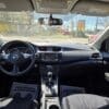 Interior view of a 2018 Nissan Sentra SV from the back seat, featuring the steering wheel, dashboard, center console, and front seats. Floor mats say YOUR BUSINESS IS APPRECIATED as sunlight shines through the windows.