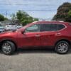 A 2015 Nissan Rogue 2.5 SL AWD is parked in a lot on a sunny day, with other vehicles and trees visible in the background.