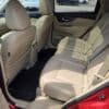 The image shows the back seat of a red 2015 Nissan Rogue 2.5 SL AWD with beige leather seats, two headrests, seatbelts, rear air vents, and an open door revealing the clean, spacious interior.