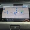 A cars GPS screen displays a map of Oshawa, ON. Various blue markers with numbers are scattered across the map. The screen shows time as 2:03, and temperature as 7°C. A search bar appears at the top. A home button is visible below the screen.