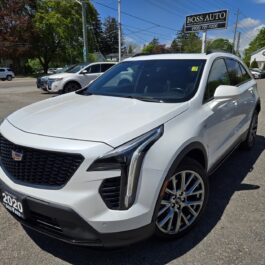 A 2020 Cadillac XT4 Sport AWD sits in a dealership lot on a sunny day, with a BOSS AUTO sign and other cars in the background.
