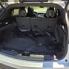 With the rear seats upright, the trunk of a 2020 Cadillac XT4 Sport AWD displays several black rubber floor mats stacked on its carpeted cargo area, illuminated by sunlight with a parking lot visible outside.