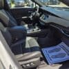 A photo of a 2020 Cadillac XT4 Sport AWD’s front interior with black leather seats, modern dashboard touchscreen, center console, AWD badge, and a passenger-side floor mat stating “Your business is appreciated!”.
