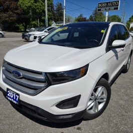 A 2017 Ford Edge SEL is parked in a car lot under a sunny sky, with other vehicles and the Boss Auto dealership sign visible in the background.