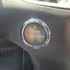 Close-up of the engine start-stop button with a green indicator light in the 2017 Ford Edge SEL, set against a black textured dashboard.