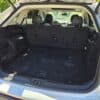 The open trunk of a 2017 Ford Edge SEL with rear seats upright highlights its spacious black cargo area, illuminated by sunlight.