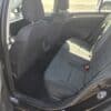 The image shows the interior of a 2015 Volkswagen Golf 1.8T Highline, featuring two rows of gray fabric seats, an open rear door, and a view of the front seats and center console with sunlight highlighting its spacious design.