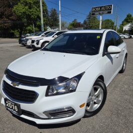 A 2016 Chevrolet Cruze 2LT Limited sedan in white is parked at BOSS AUTO dealership on a sunny day, surrounded by other vehicles and trees.