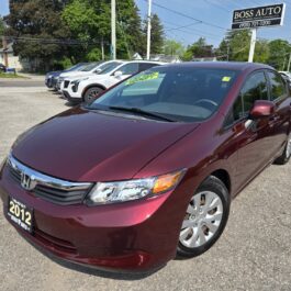 A 2012 Honda Civic LX is parked outside a dealership with a Boss Auto sign, other cars in the background, and a green for sale sign on its windshield.