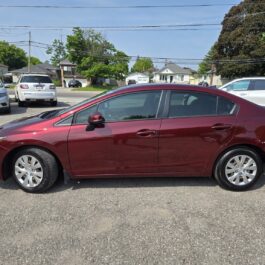 A 2012 Honda Civic LX in maroon is parked in a lot on a sunny day, with houses and other cars visible in the background.