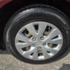Close-up of a silver Honda wheel with black tire on a 2012 Honda Civic LX, parked on asphalt. The hubcap displays the Honda logo and five curved spokes, with the tire and wheel well in view.