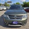 A 2017 Dodge Journey Crossroad V6 AWD in green is parked at a car dealership lot, with other vehicles and the BOSS AUTO sign visible in the sunny background.