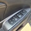 Close-up of the 2017 Dodge Journey Crossroad V6 AWD’s door control panel, showing window, lock, and side mirror controls in black and silver trim with refined detailing.