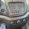 The dashboard of a 2017 Dodge Journey Crossroad V6 AWD features a touchscreen radio tuned to 104.5 FM playing Abracadabra by Lady Gaga, with visible climate control knobs and partial steering wheel and floor mat.