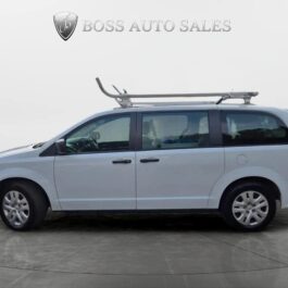A light gray 2019 Dodge Grand Caravan SE Plus CARGO minivan with a roof rack is parked indoors on a gray floor. The Boss Auto Sales logo appears at the top of the image.