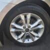 Close-up of a silver 2013 Kia Optima EX wheel featuring a five-spoke alloy rim and a General Evertrek tire, parked on asphalt.
