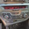 A 2013 Kia Optima EX climate control panel shows both temps at Lo, red digital display, A/C on, seat warmers off, and the passenger airbag indicator reads OFF. The time displayed is 7:59.