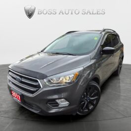 A gray Ford SUV is displayed in a showroom with Boss Auto Sales on the wall behind it. The SUV has a 2017 license plate and is parked on a circular platform with a clean, modern backdrop.