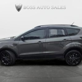 A dark gray SUV with tinted windows and black wheels is parked indoors on a circular platform. Boss Auto Sales logo and text are displayed above the vehicle against a plain, light background.
