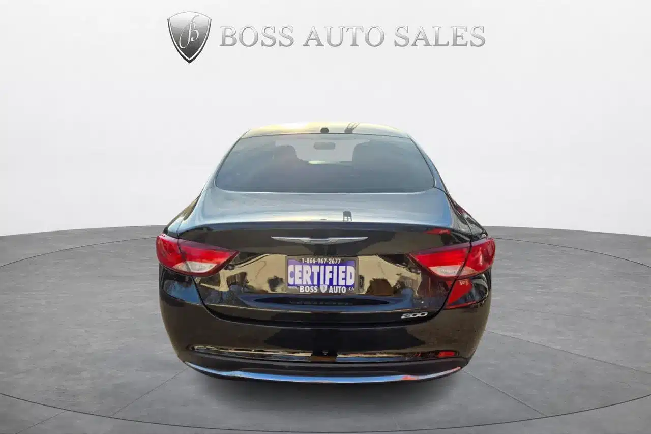 A 2015 Chrysler 200 Limited, black sedan, is shown from the rear on a circular platform at BOSS AUTO SALES, featuring a Certified sign on its license plate area.