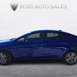 A 2020 Hyundai Elantra Preferred sedan is parked indoors on a circular platform, viewed from the side. The plain background features Boss Auto Sales and a shield logo above the car.