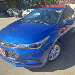 A blue Chevrolet Cruze parked in a gravel lot.